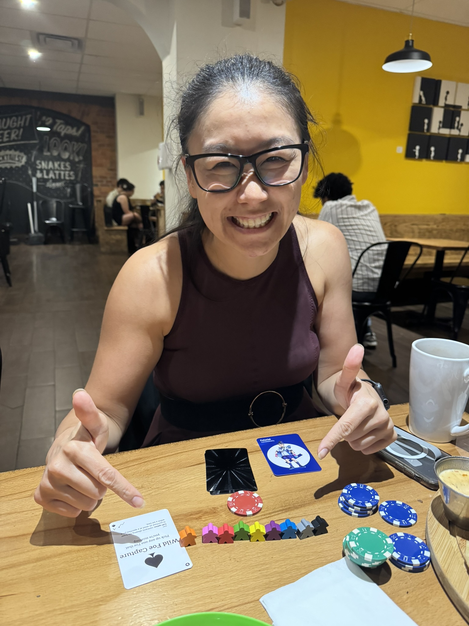 Player laughing and fully engaged during a Game of Gains session at Snakes and Lattes in Toronto